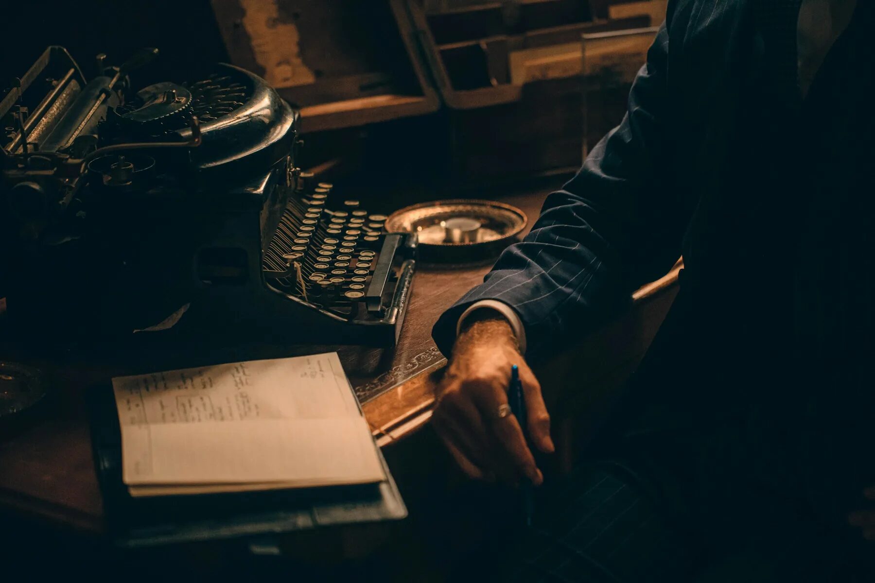 Man in a pinstripe suit seated beside a vintage typewriter